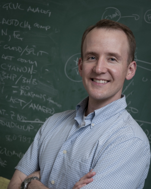 image of Ross Carlson man in a collar shirt standing in front of a chalkboard